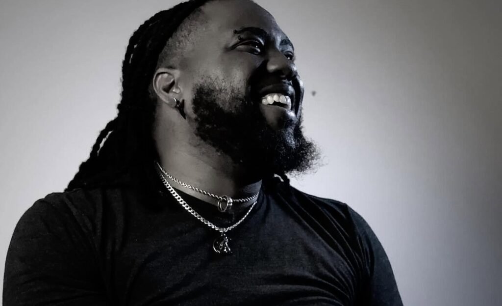 Poet Derek Light posing against a backlit background during a headshot shoot.